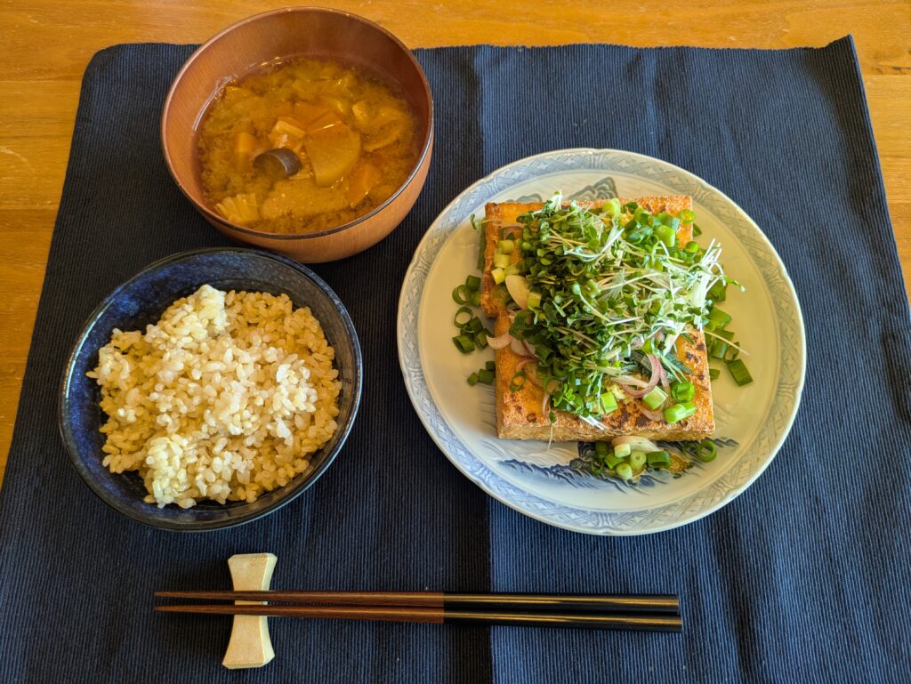 玄米、具沢山味噌汁、薬味たっぷりの厚揚げの写真